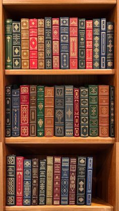 several books are stacked on top of each other in a wooden bookcase with red and blue covers