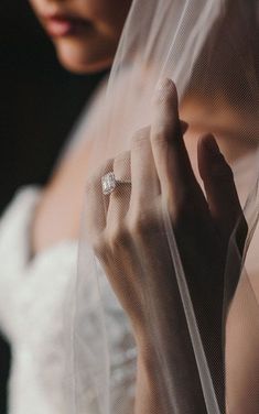 a close up of a person wearing a wedding dress and holding a veil over their face