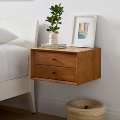 a bedroom with a bed, nightstand and potted plant on the end table next to it