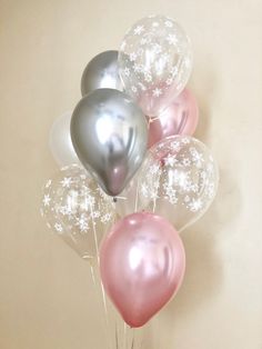 a bunch of balloons that are sitting in a vase on a table next to a wall