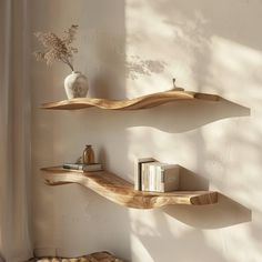 two wooden shelves on the wall with books and vase next to each other in front of a window