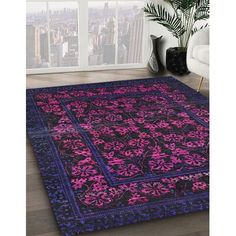 a purple and black area rug with pink flowers on the bottom, in front of a large window