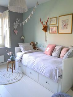 a white bed sitting in a bedroom next to a window with pictures on the wall