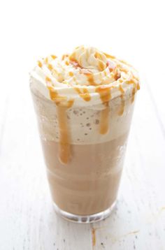 an iced drink with caramel drizzle and whipped cream on the top is sitting on a white table