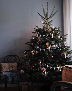 a small christmas tree with ornaments on it in a living room next to a window