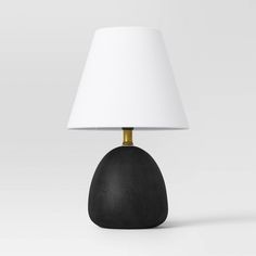 a black table lamp with a white shade on it