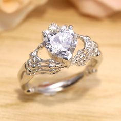 a heart shaped diamond ring sitting on top of a wooden table