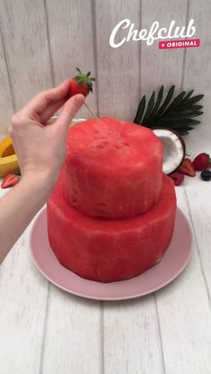 someone is cutting into a strawberry cake on a plate