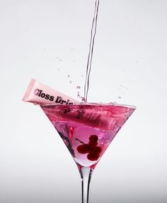 a pink martini drink being poured into a glass with a candy bar in the middle