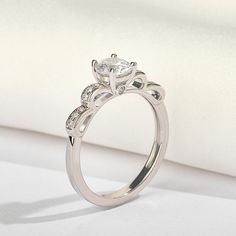 a white gold engagement ring with an oval cut diamond center surrounded by smaller round diamonds