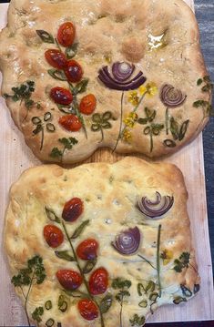 two pizzas with tomatoes, onions and herbs on them sitting on a cutting board