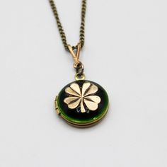 "A tiny brass locket opens to hold two photographs that we place for you.  This piece features an antiqued brass four leaf clover against an emerald green enamel. ~1/2\" ~Photos with one or two close together subjects work best *Made to order.  Please allow 5-10 business days for production." Vintage Charm Green Brass Necklaces, Green Brass Necklaces With Vintage Charm, Antique Green Locket Jewelry, Vintage Brass Jewelry For Good Luck, Green Antique Finish Jewelry For Gift, Green Vintage Charm Brass Jewelry, Green Brass Jewelry With Vintage Charm, Brass Locket Necklace With Charms For Keepsake, Vintage Good Luck Locket Jewelry