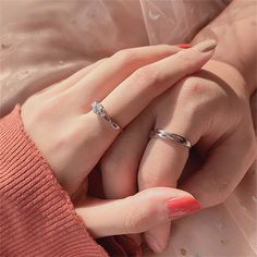 two hands holding each other with wedding rings on their fingers and pink manicures