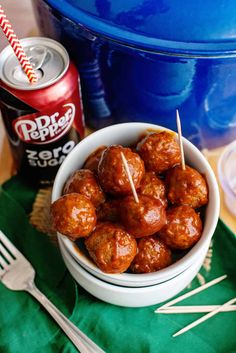 a bowl filled with meatballs next to a can of soda