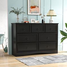 a black dresser sitting on top of a hard wood floor next to a blue wall