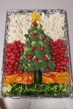 a christmas tree made out of veggies and other vegetables on tin foil with red peppers