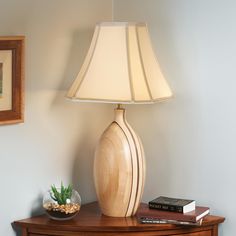 a lamp is sitting on top of a table next to a potted plant and books