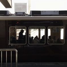 people are sitting in the window of a commuter train as it pulls up to the station