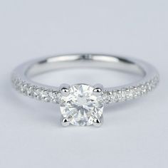 a white gold engagement ring with a round brilliant cut diamond in the center and pave set shoulders