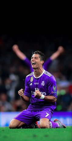 a soccer player sitting on the ground with his arms in the air