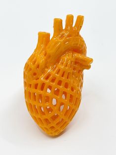 an orange plastic model of a heart on a white surface with holes in the middle