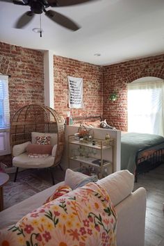 a living room filled with furniture next to a bed and a brick wall behind it