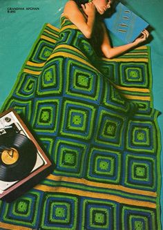 a woman laying on top of a blanket next to a record player and an album