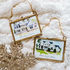 two framed pictures sitting on top of a white blanket next to a gold chain necklace