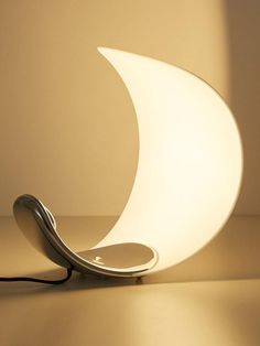 a lamp that is shaped like the moon and has a cord attached to it, sitting on a table