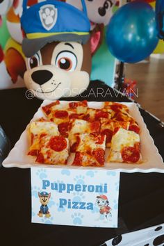 there is a plate of pizza on the table next to a stuffed bear and balloon