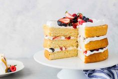 a piece of cake with white frosting and berries on top sits on a plate