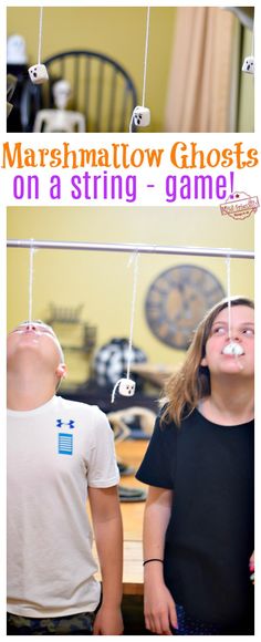 two children standing next to each other with marshmallow ghosts on a string in front of them