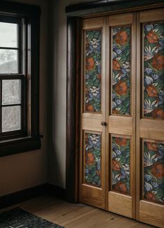 an open wooden door in front of a window with floral wallpaper on the doors