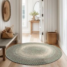 a room with white walls, wooden floors and a round rug on the floor next to a bench