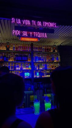 people sitting in front of a bar with neon lights