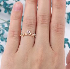 a woman's hand with a ring on it and flowers in the back ground