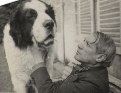 an old black and white photo of a man petting a dog on the nose