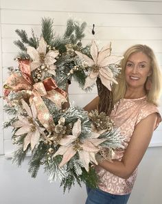 a woman holding a christmas wreath with poinsettis and pine cones on it