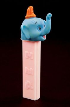 an elephant figurine sitting on top of a plastic tube with its trunk sticking out