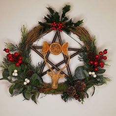 a pentagramil with antlers, pine cones and holly wreaths around it