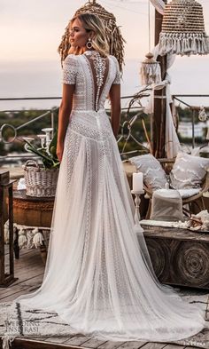 a woman in a wedding dress is standing on a deck with her back to the camera