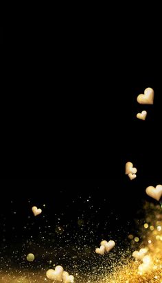 some white hearts are flying in the air with gold glitter around them on a black background