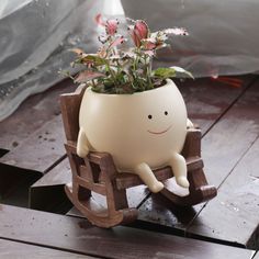 a planter with flowers in it is sitting on a wooden bench and has its legs spread out