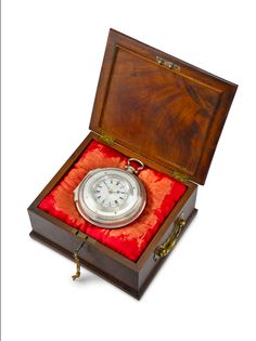 an open wooden box with a silver clock inside