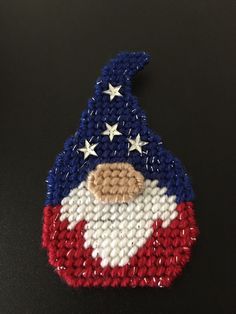 a knitted santa clause hat with stars and stripes on the side, sitting on a black surface