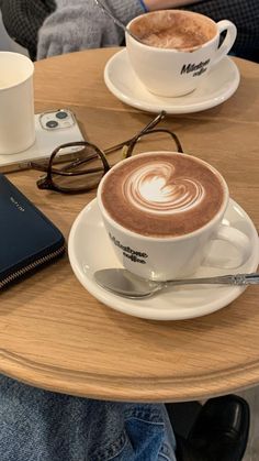 there is a cup of coffee on the table next to a cell phone and glasses