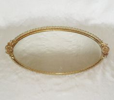 a gold oval mirror sitting on top of a white blanket