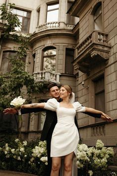 a man and woman are posing in front of a building