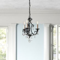 a chandelier hanging from the ceiling in a dining room with blue walls and windows