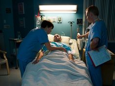 two doctors and an elderly man in a hospital bed